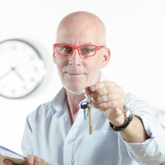 Bild eines Hausbesitzers, der einen Schl&uuml;ssel h&auml;lt.